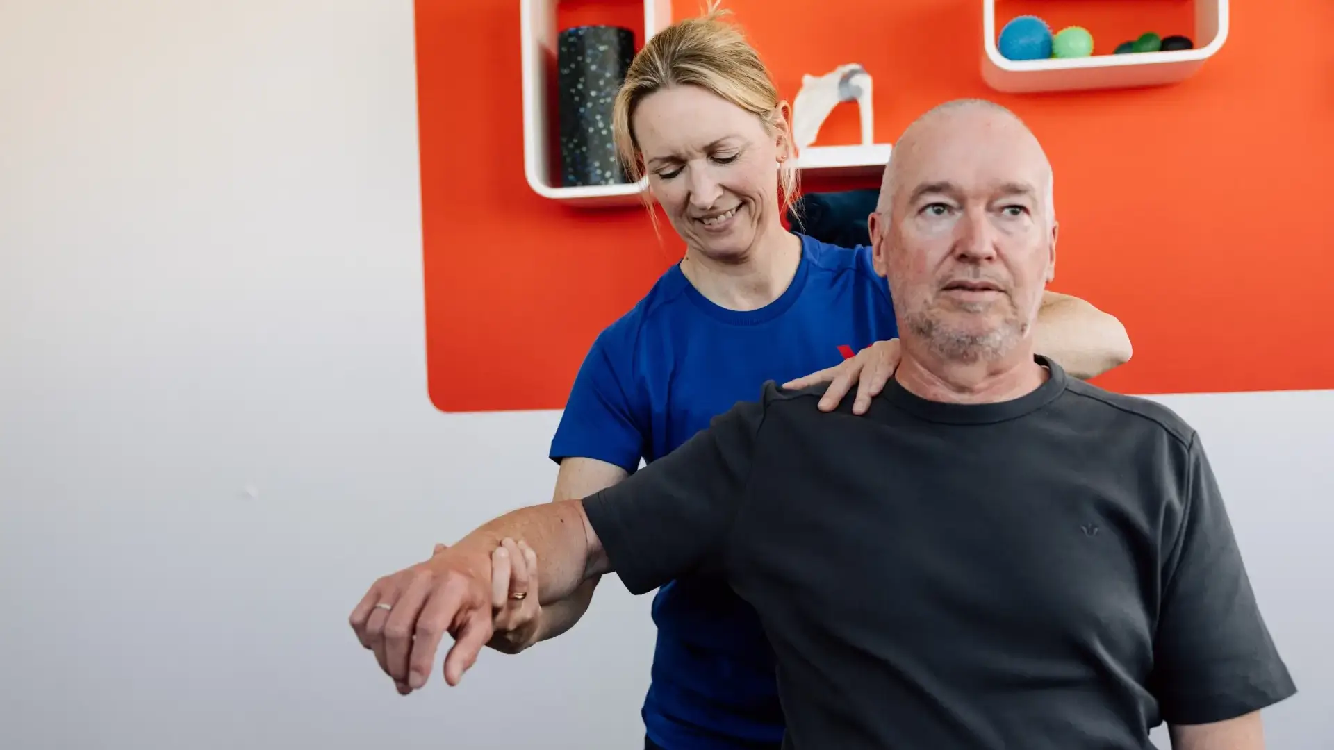 Physiotherapeutin führt Schulter- und Armübungen mit männlichem Patienten durch.