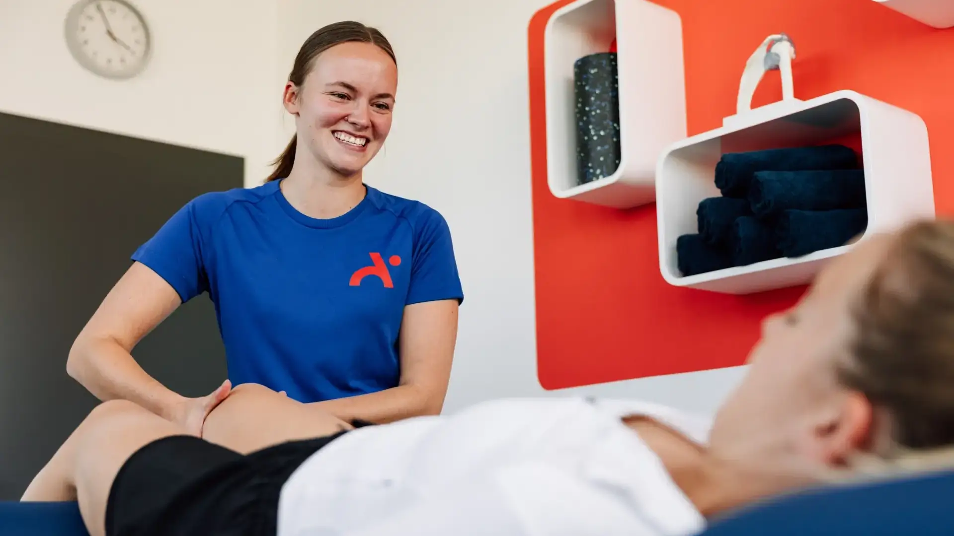 Physiotherapeutin führt mit einem Lächeln eine Kniebehandlung bei einer Patientin durch.