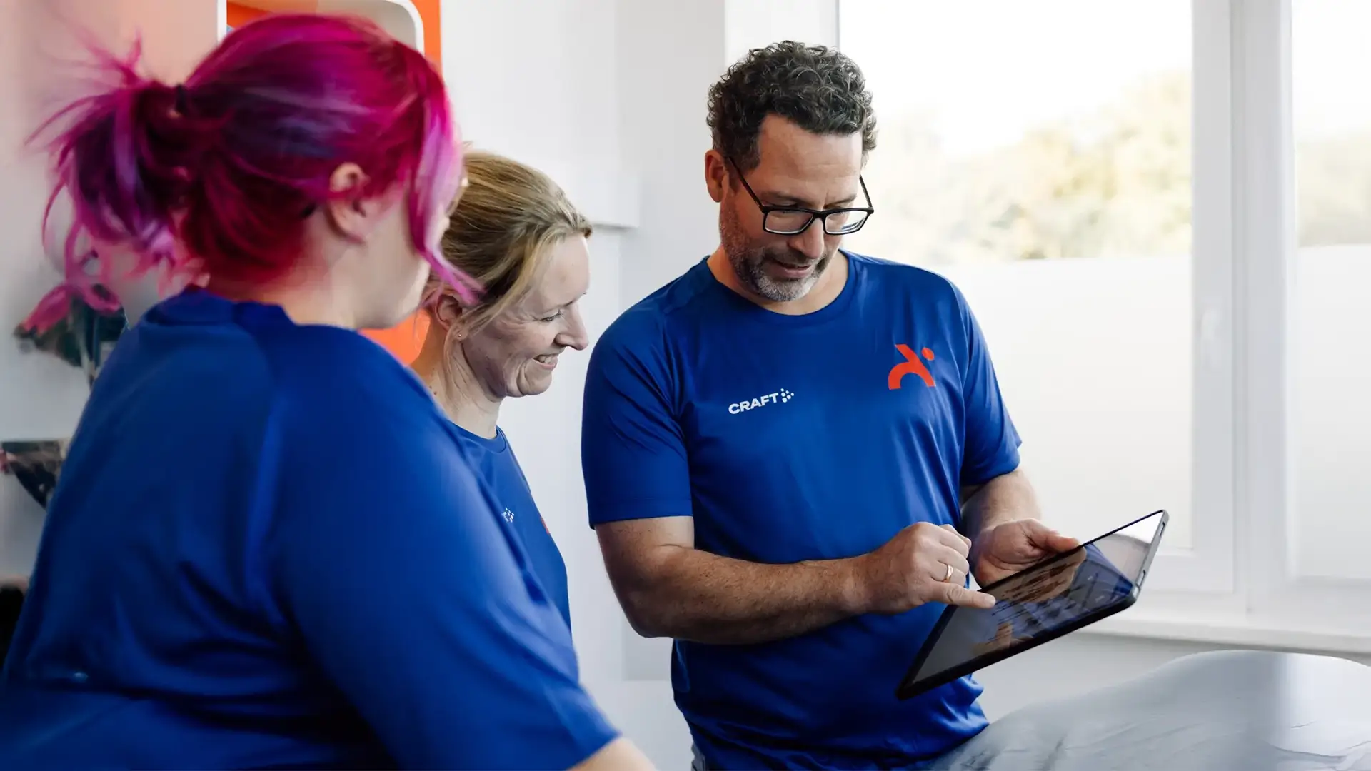 Team der Physiotherapie Ambrassat bespricht Patientendaten gemeinsam am Tablet.