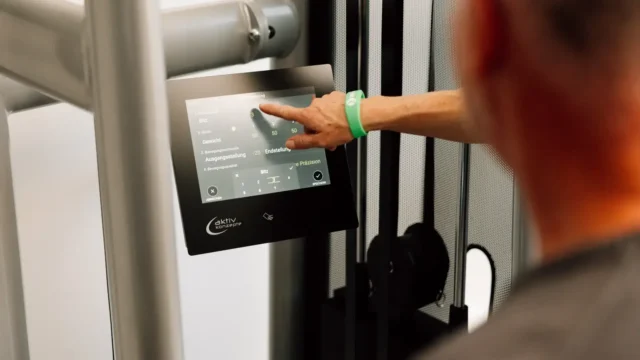 Nahaufnahme eines Patienten, der die Einstellungen an einem digitalen Trainingsgerät vornimmt.