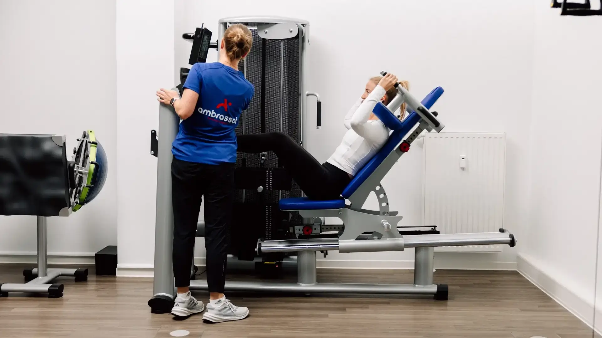 Physiotherapeutin betreut Patientin an der Beinpresse während einer Trainingseinheit.