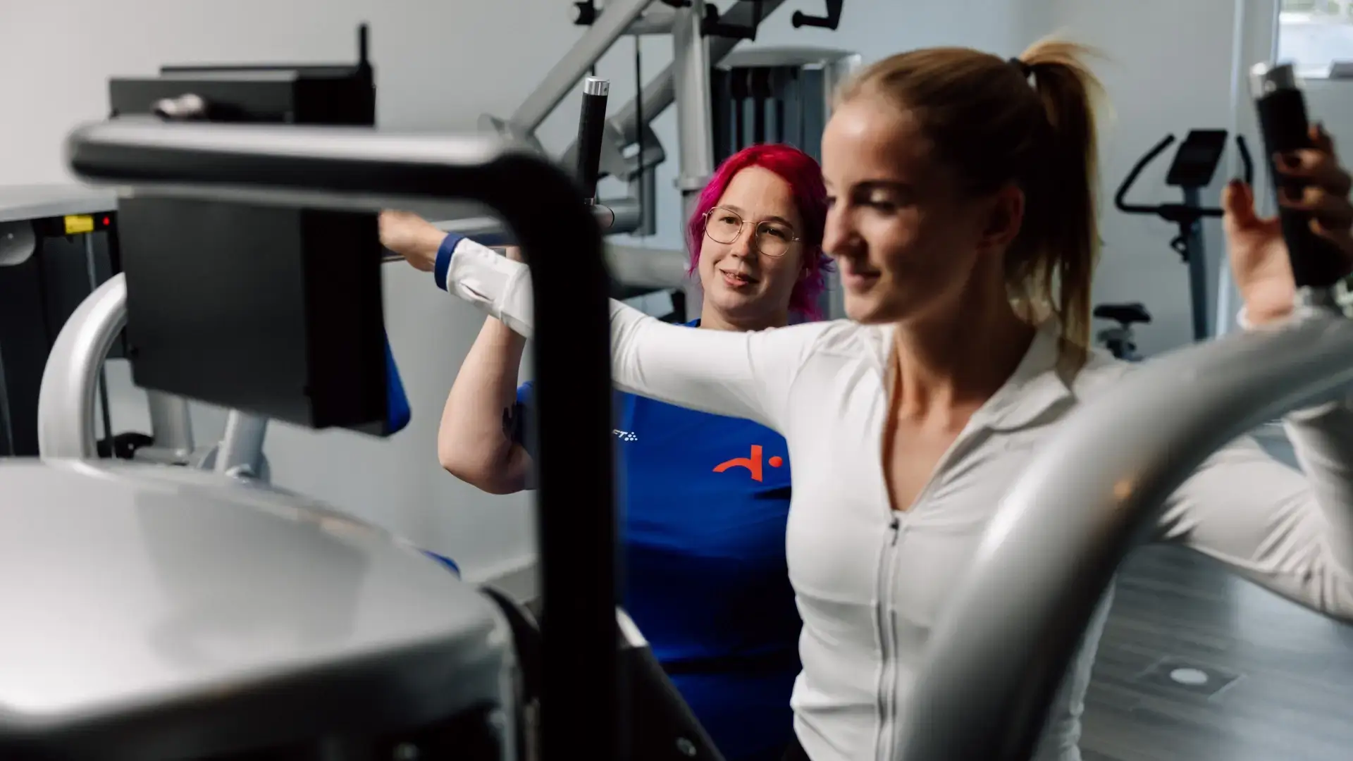 Physiotherapeutin betreut Patientin während einer Übung an der Kraftmaschine.